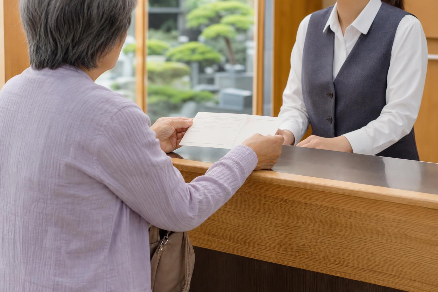 墓地管理事務所の窓口で管理料について相談している様子